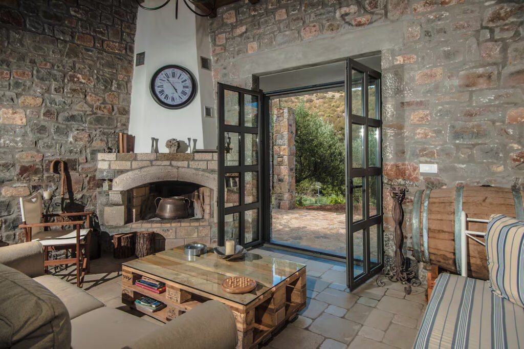 Τζάκι στο σαλόνι του Elaiodentron eco House με θέα στο κεδρόδασος της Ανατολικής Κρήτης